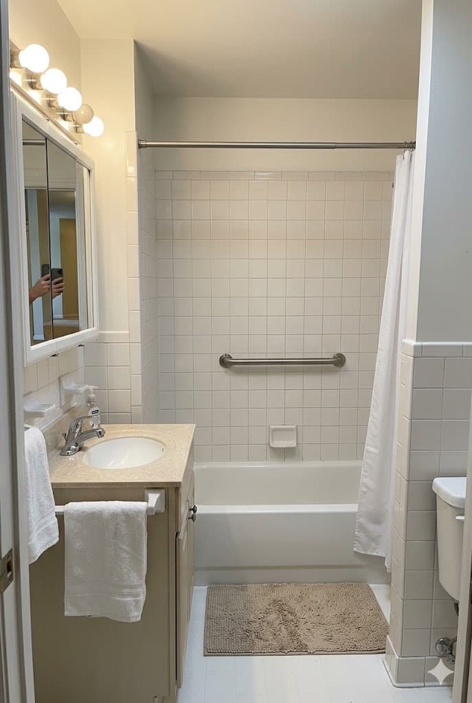 A stainless steel grab bar installed in a tiled bathtub and shower surround.