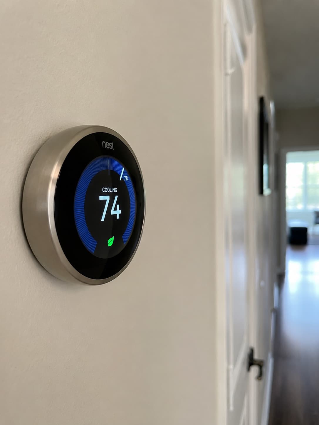 A smart thermostat mounted on a wall displaying the room temperature.