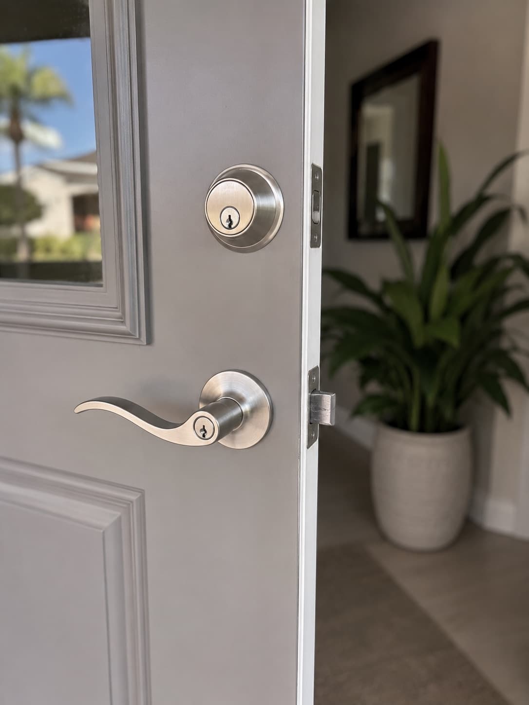 A new brushed-nickel deadbolt and lever handle installed on a front door.